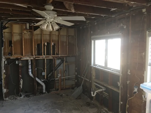Kitchen framing with wood studs, window opening, HVAC ducts, and electrical rough-in