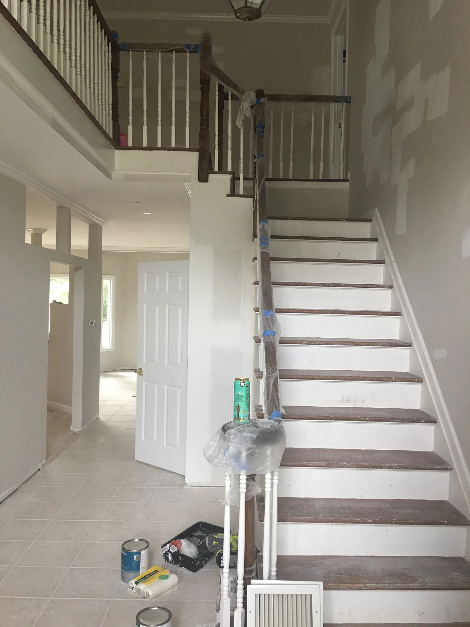 Staircase with dark wood treads, white risers, and white spindle railings during renovation