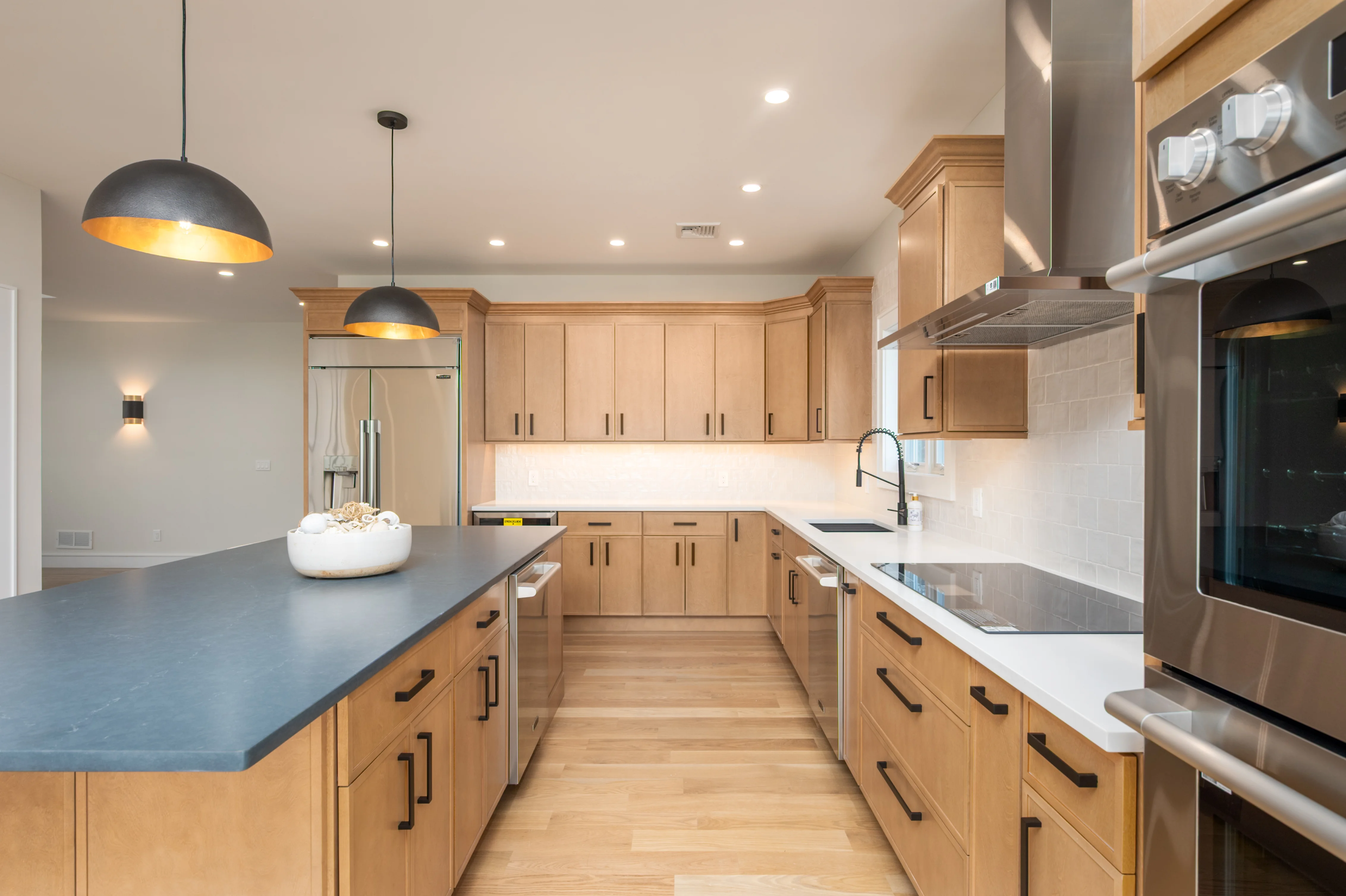 Modern kitchen with oak cabinets, blue quartz counters, white tile backsplash, stainless steel appliances