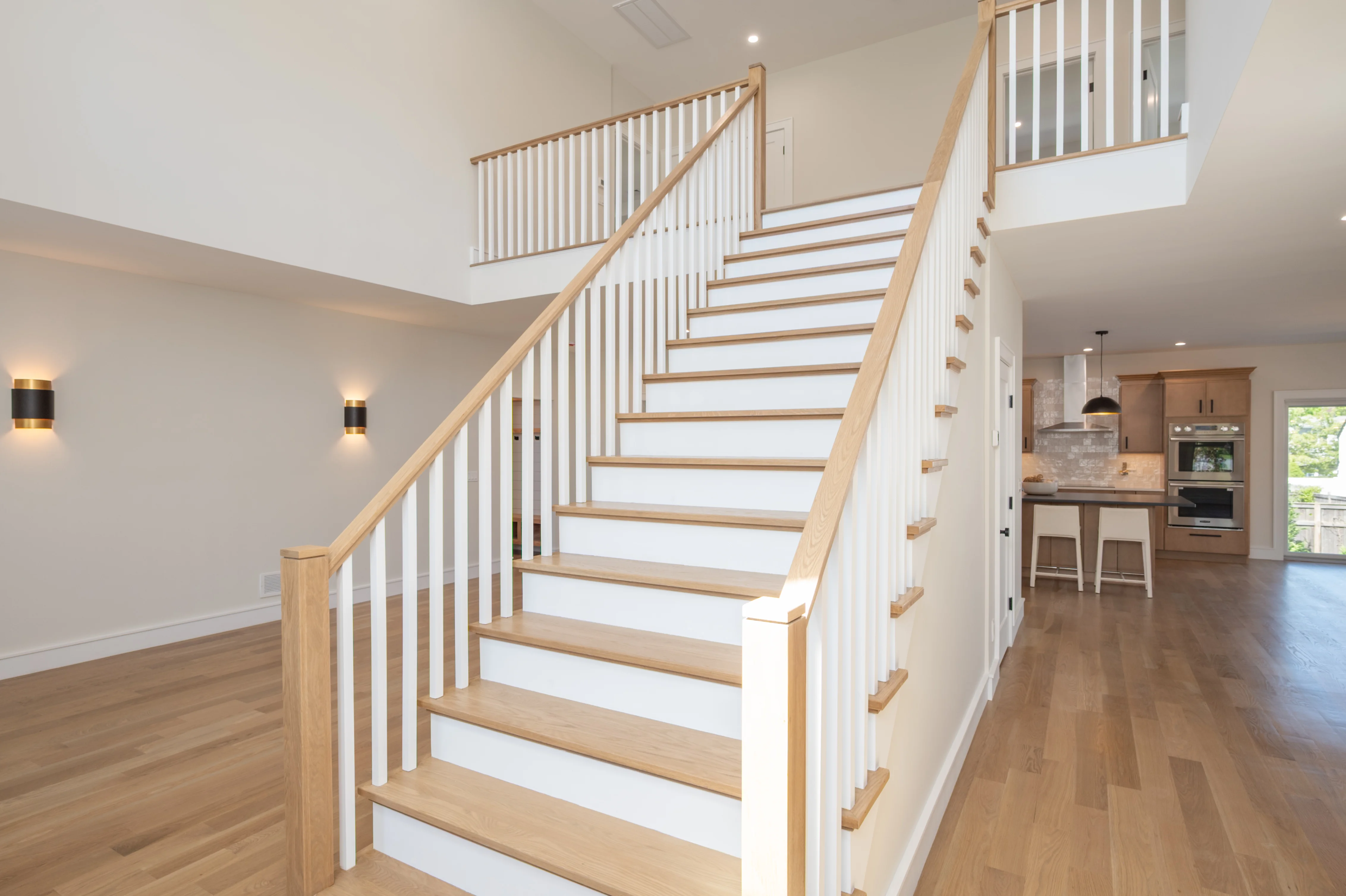 Natural wood staircase with white spindle railings and wood handrails in open concept home