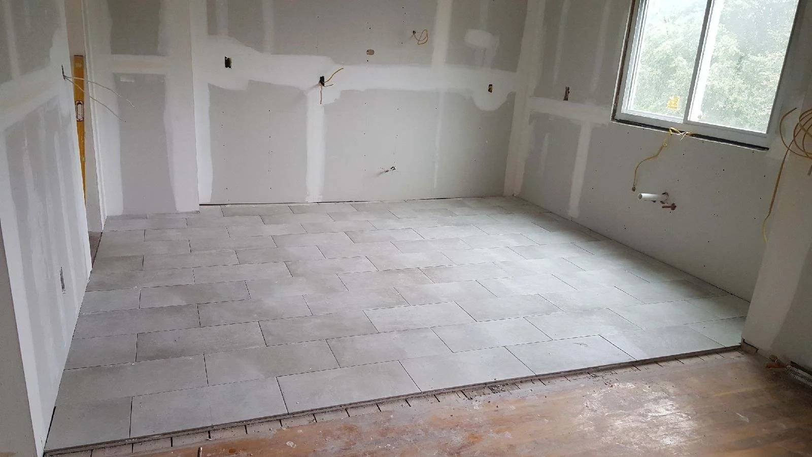 Kitchen with herringbone ceramic tile flooring and finished drywall walls during renovation