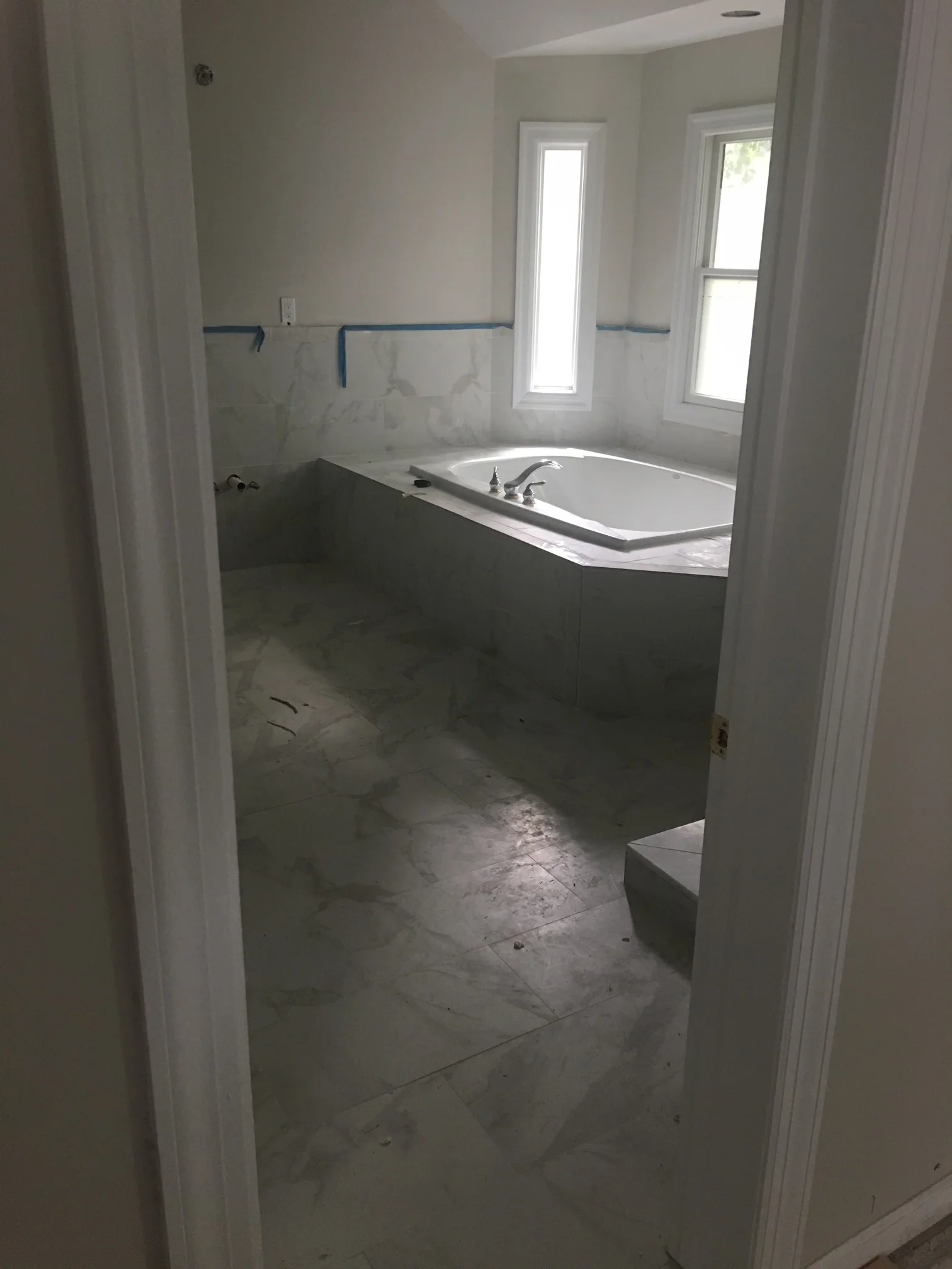 Bathroom renovation with marble tile wainscoting, soaking tub, and drywall installation in progress