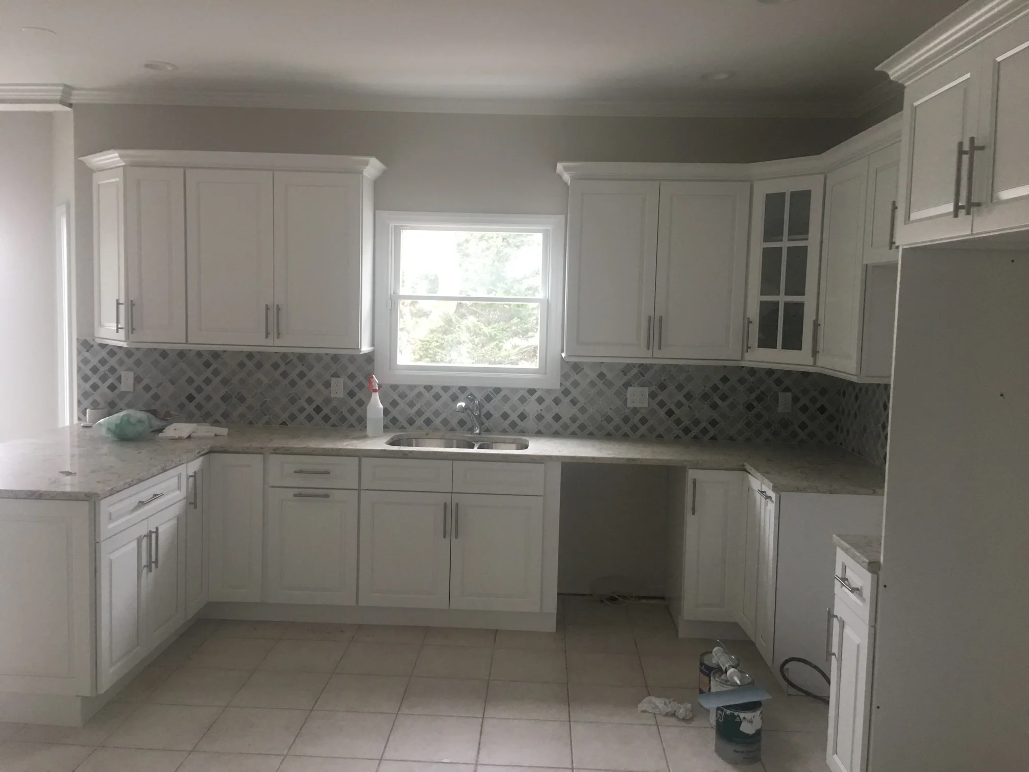 White kitchen cabinets with gray diamond tile backsplash and quartz countertops
