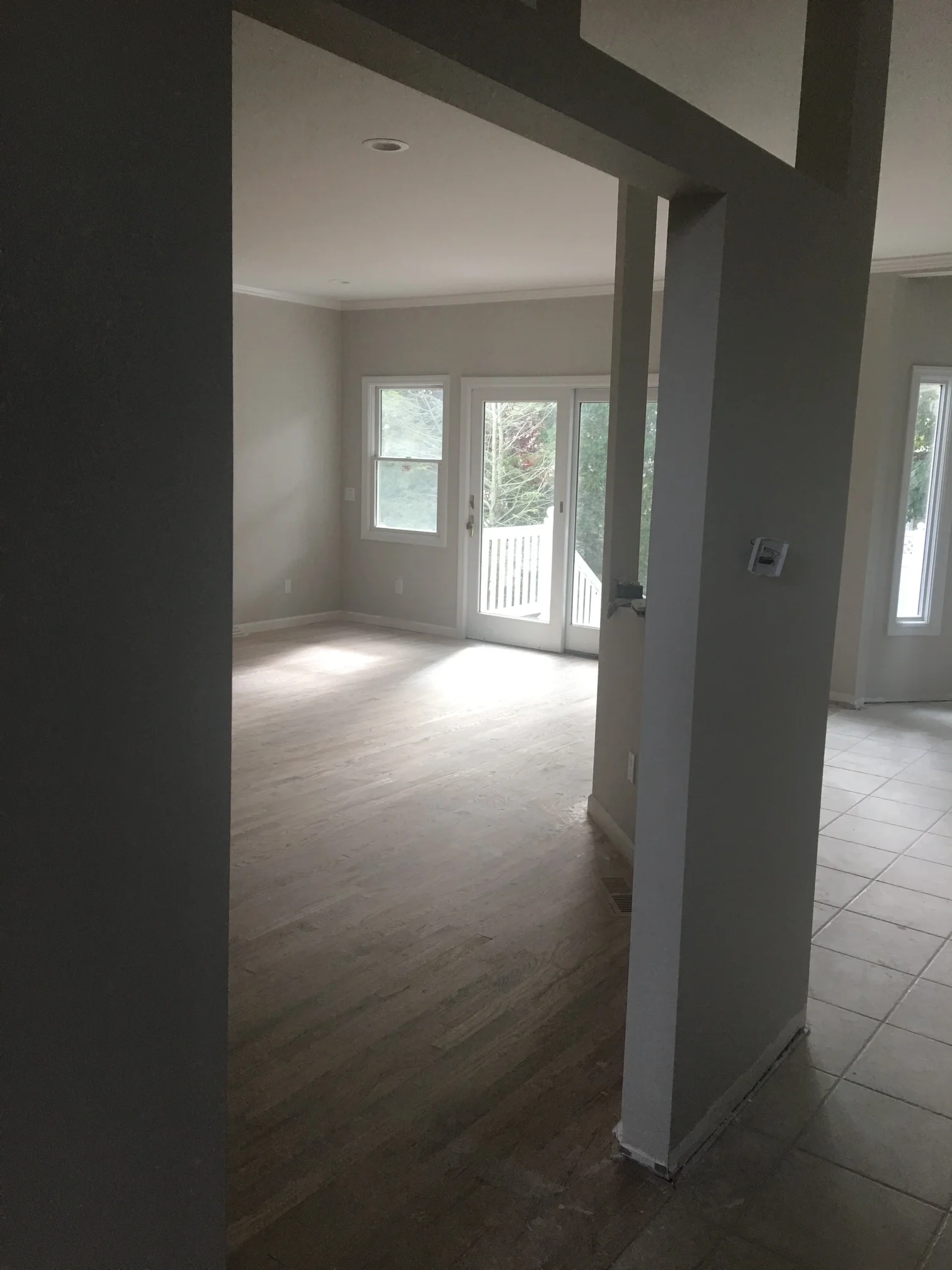 Bright interior room with white drywall, recessed lights, glass sliding doors, and mixed flooring materials