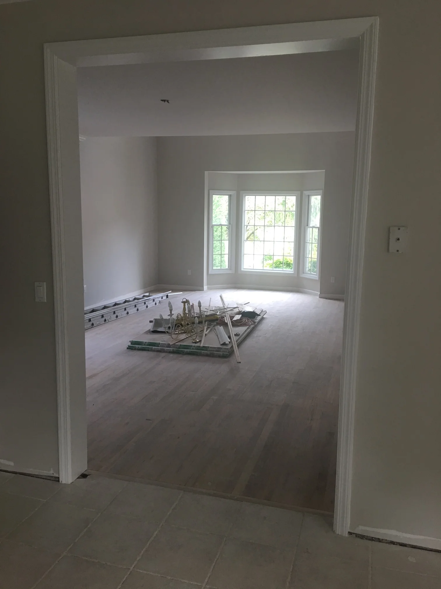 Renovated room with white drywall, primed walls, and installed bay window with white trim