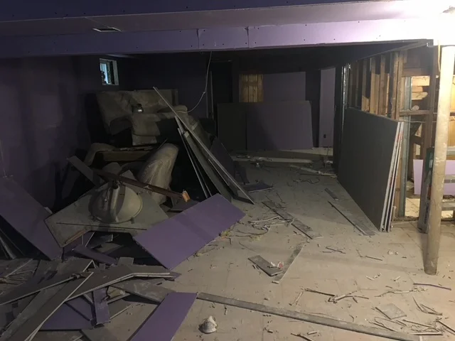 Commercial interior demolition with exposed framing, removed drywall, and debris cleanup