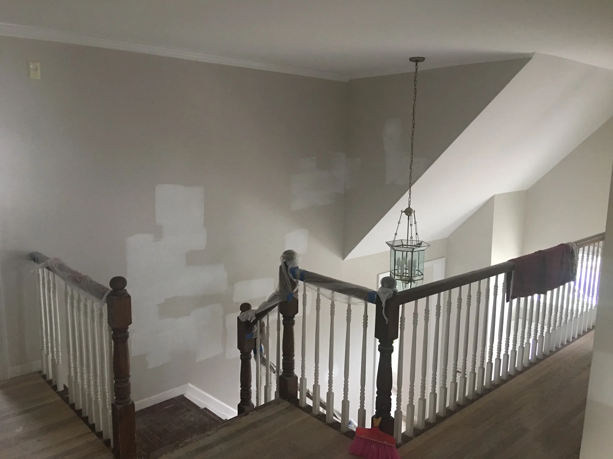 Second floor landing with white drywall, sloped ceiling, dark wood and white spindle railing system