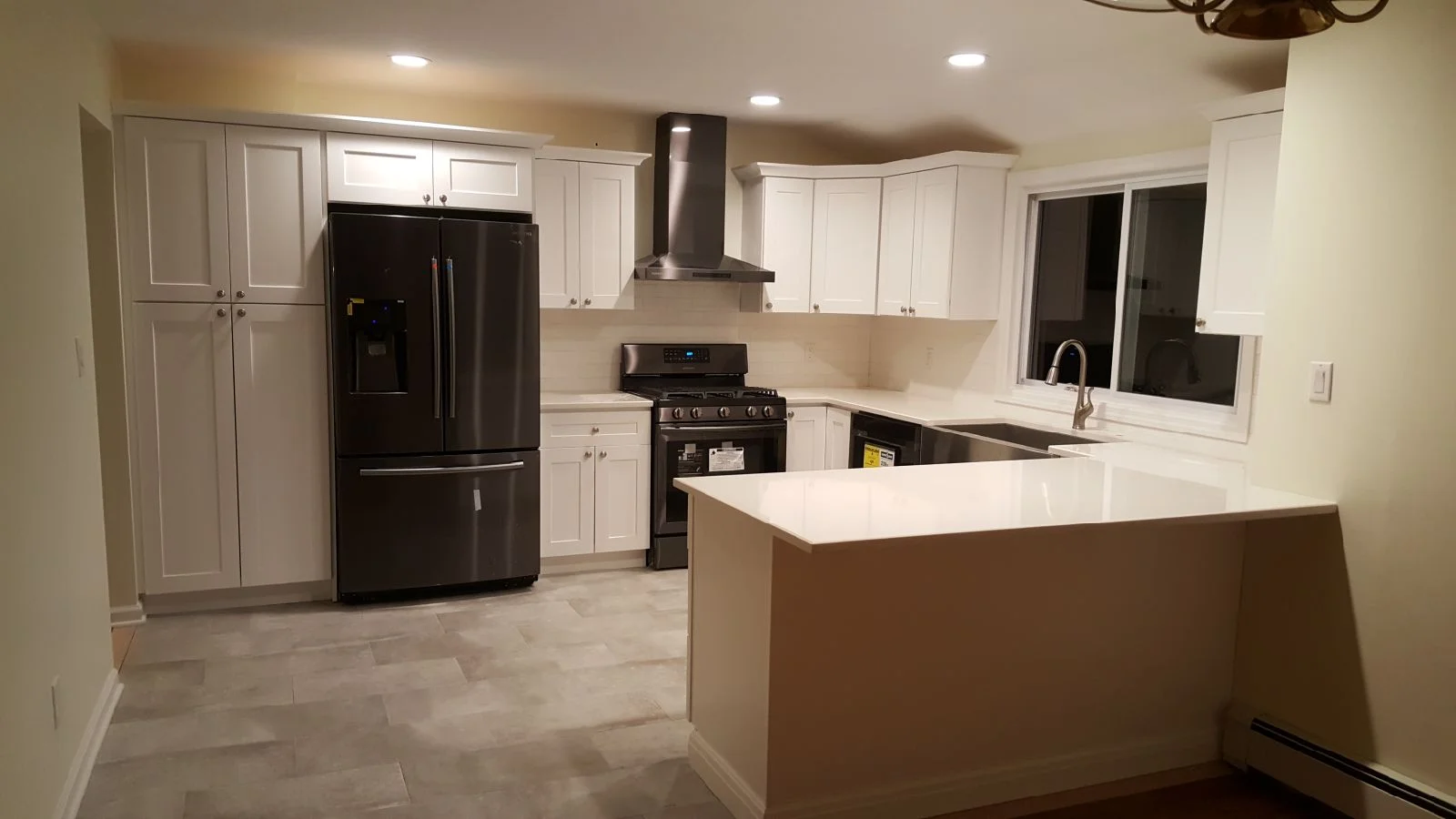 White cabinetry kitchen with black appliances, quartz island countertop, and tile flooring