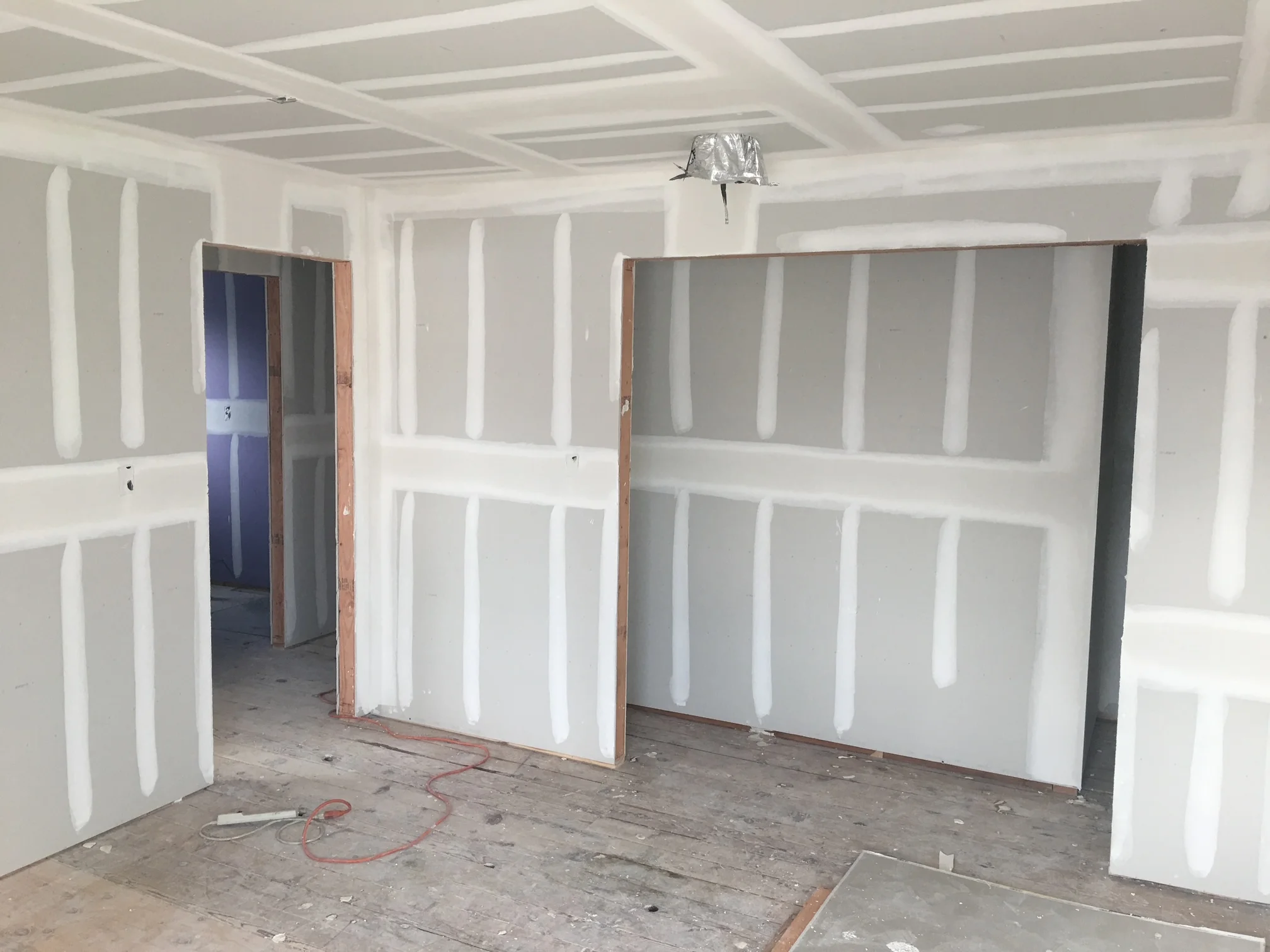 Garage interior with white drywall walls, coffered ceiling, and two large garage doors with wood frames