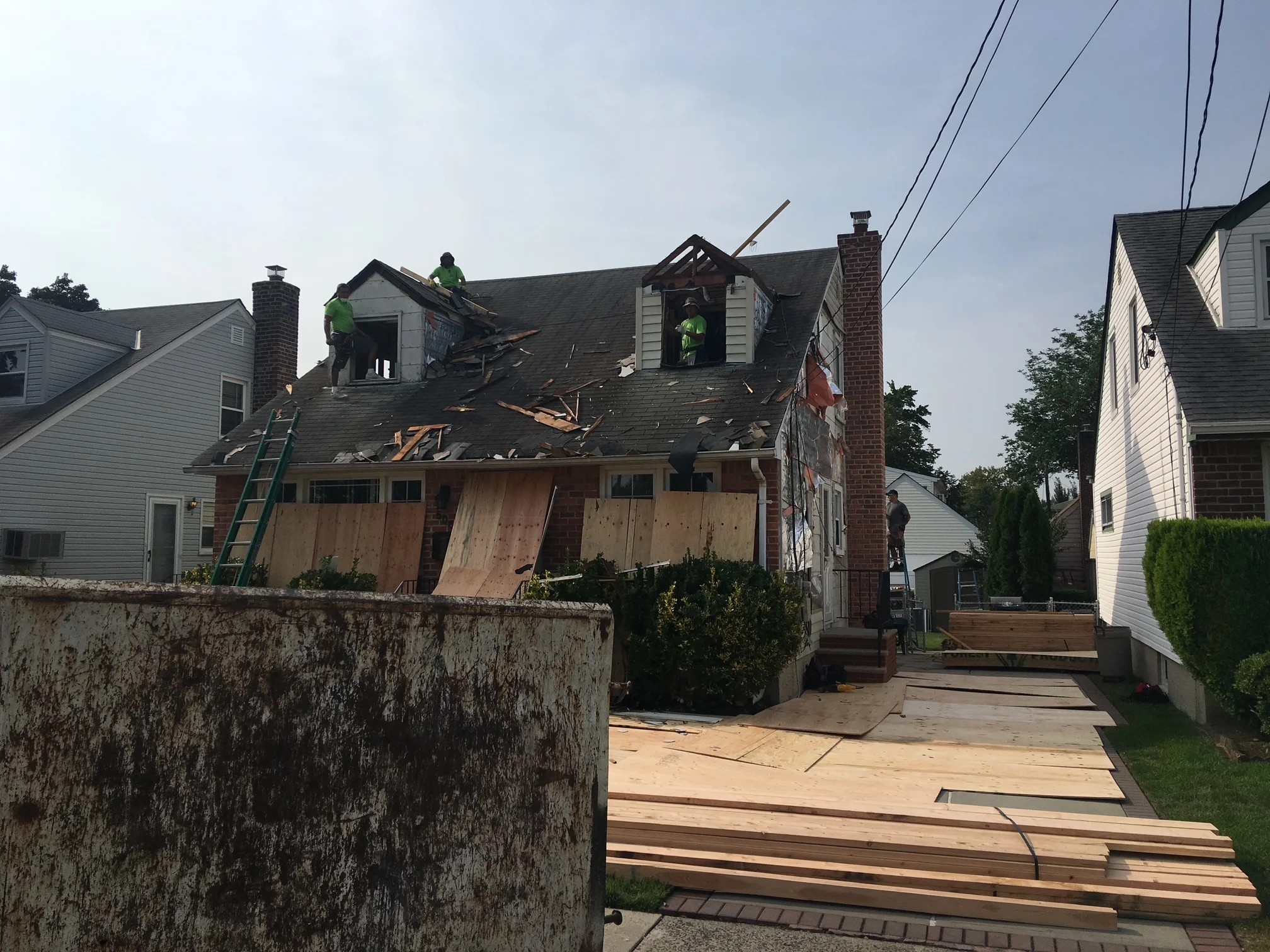 Fire-damaged roof with removed shingles, exposed framing, and new lumber sheathing installation in progress