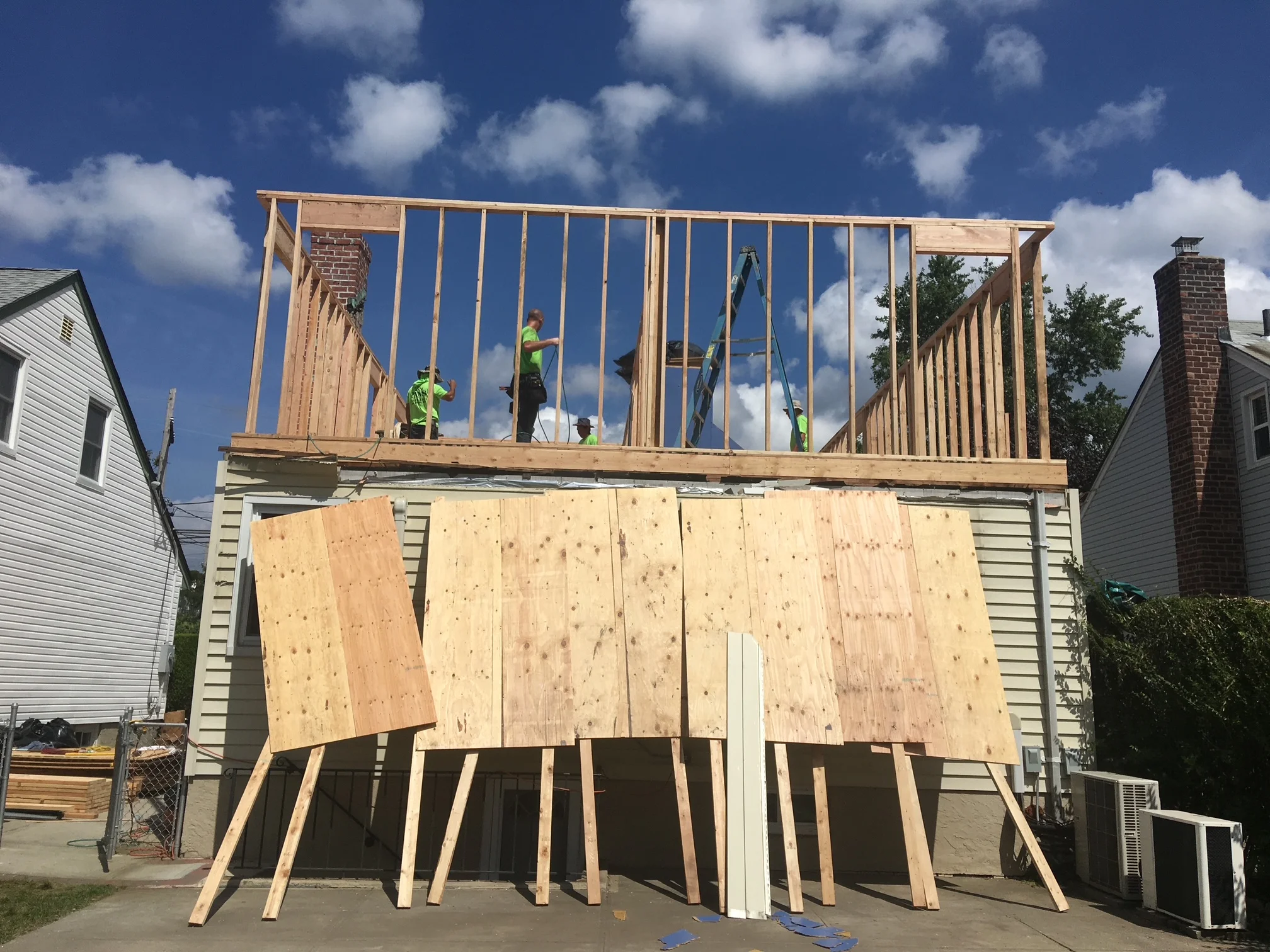 Second story wood framing with studs, plywood sheathing, and window openings under construction